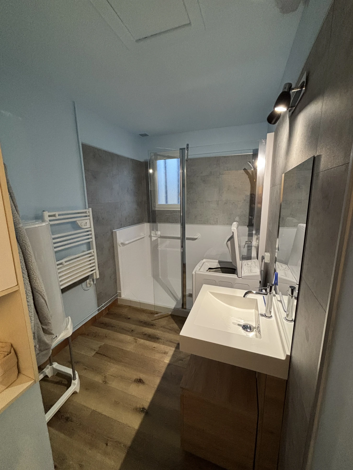 Salle de bain avec douche sécurisée, sol antiderapant, dalles murales pvc gris, vasque surélevée avec meuble sur roulette